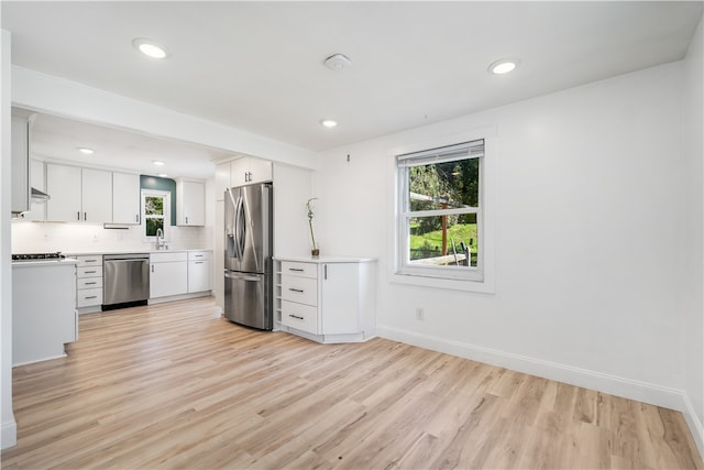 kitchen featuring sink, stainless steel appliances, decorative backsplash, white cabinets, and light wood-type flooring