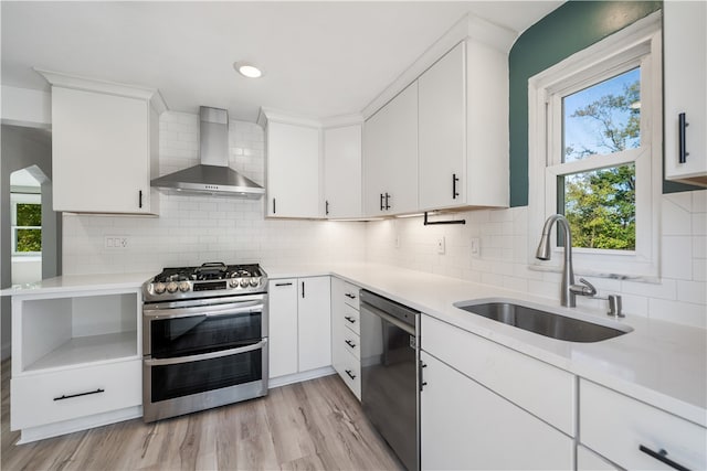 kitchen with white cabinets, sink, wall chimney exhaust hood, and appliances with stainless steel finishes