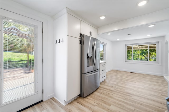 kitchen with stainless steel fridge, light wood-type flooring, and a wealth of natural light