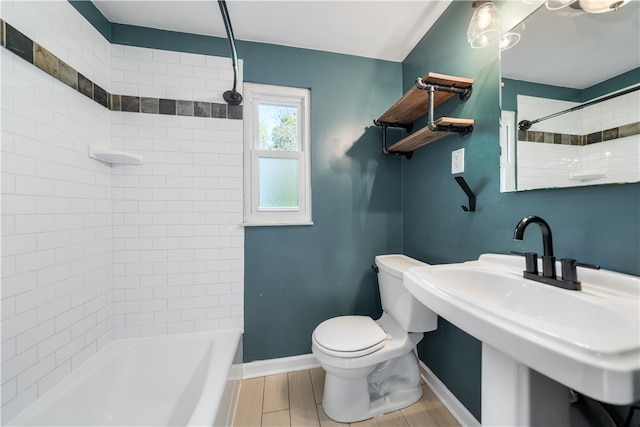 full bathroom featuring hardwood / wood-style floors, tiled shower / bath combo, toilet, and sink