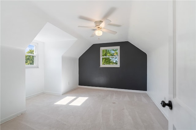 additional living space with light carpet, vaulted ceiling, plenty of natural light, and ceiling fan