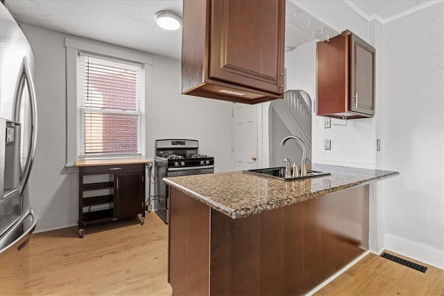 kitchen featuring dark stone countertops, sink, stainless steel appliances, and light hardwood / wood-style floors