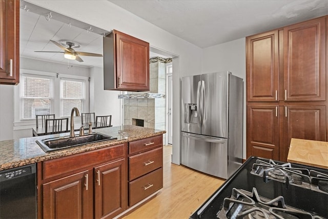 kitchen featuring ceiling fan, sink, light stone counters, light hardwood / wood-style flooring, and appliances with stainless steel finishes