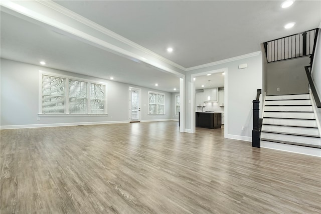 unfurnished living room with light wood-type flooring and crown molding