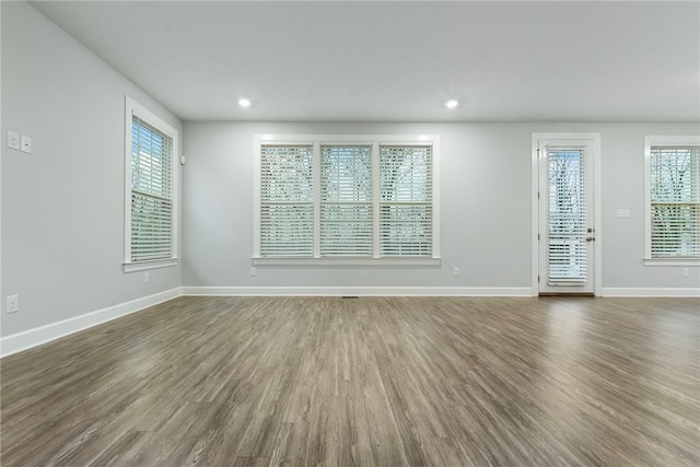 unfurnished room with a healthy amount of sunlight and dark wood-type flooring