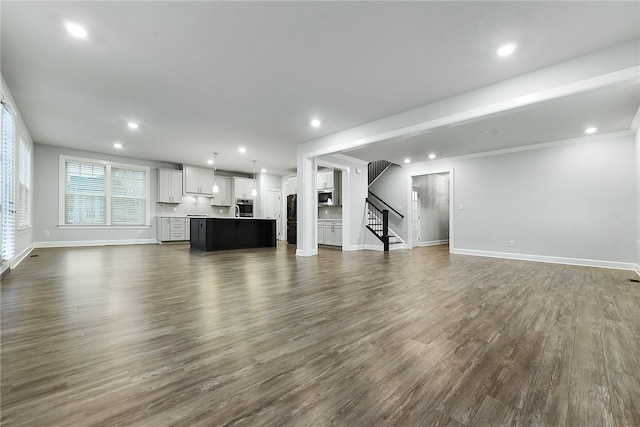 unfurnished living room featuring dark wood-type flooring and ornamental molding