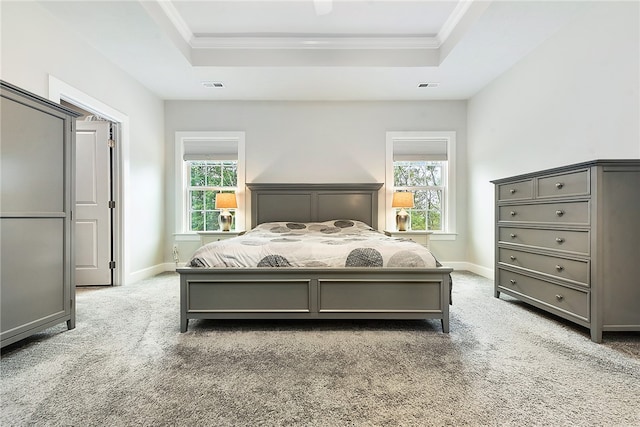 bedroom with a raised ceiling, carpet floors, crown molding, and multiple windows