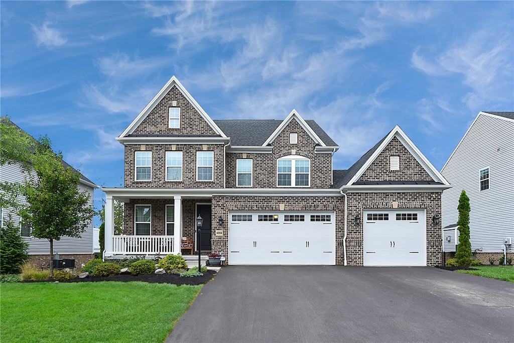 craftsman-style house featuring covered porch, a garage, and a front yard