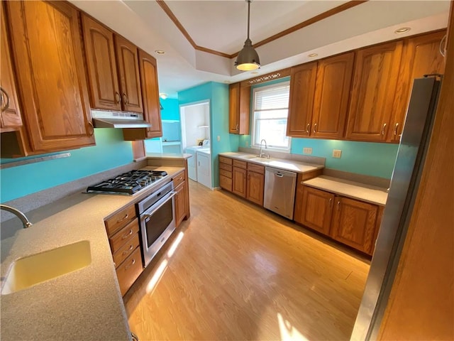 kitchen featuring decorative light fixtures, sink, stainless steel appliances, and washing machine and clothes dryer