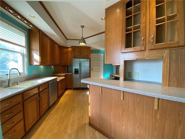 kitchen featuring sink, hanging light fixtures, kitchen peninsula, vaulted ceiling, and appliances with stainless steel finishes