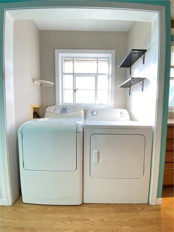 laundry room with washer and clothes dryer and light hardwood / wood-style floors