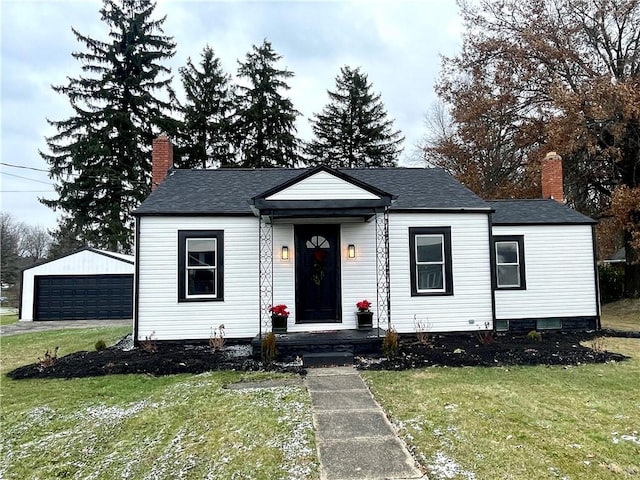 view of front facade with a front yard, an outbuilding, and a garage