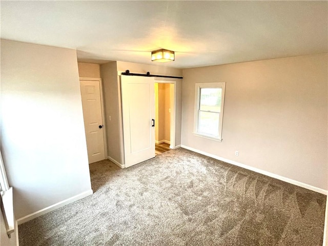 unfurnished bedroom with a barn door and carpet