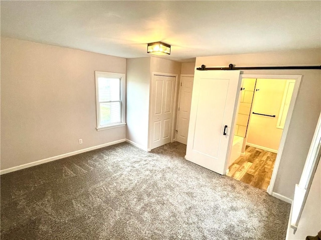 unfurnished bedroom with carpet flooring, a barn door, and a closet