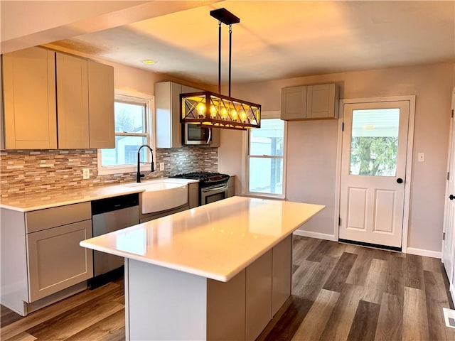 kitchen with gray cabinetry, sink, dark wood-type flooring, pendant lighting, and appliances with stainless steel finishes