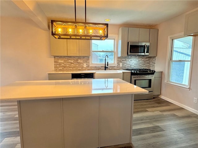 kitchen with a healthy amount of sunlight, sink, stainless steel appliances, and decorative light fixtures