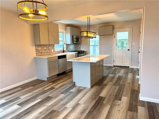 kitchen featuring gray cabinetry, a kitchen island, hanging light fixtures, and appliances with stainless steel finishes