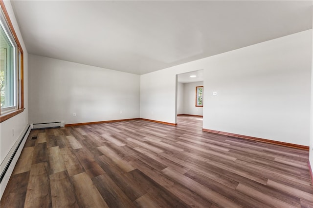 spare room featuring a baseboard heating unit and hardwood / wood-style flooring