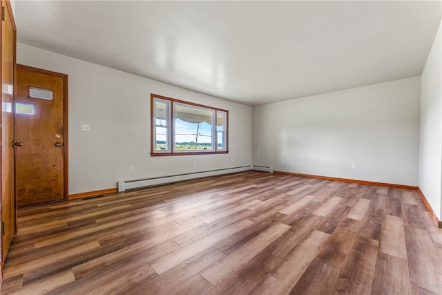 empty room featuring hardwood / wood-style floors and a baseboard heating unit