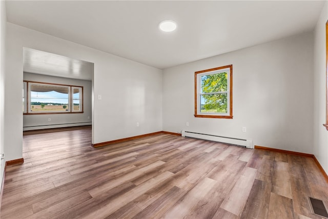 empty room with light wood-type flooring, plenty of natural light, and baseboard heating