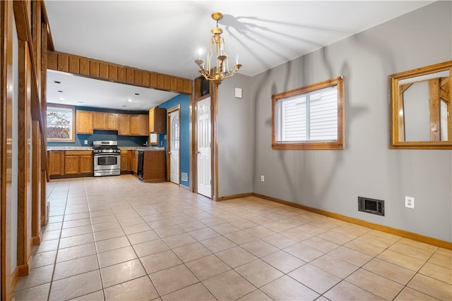 kitchen with light tile patterned floors, stainless steel gas stove, an inviting chandelier, and plenty of natural light