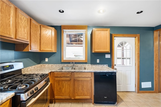 kitchen featuring dishwasher, sink, stainless steel gas range, light stone countertops, and light tile patterned floors