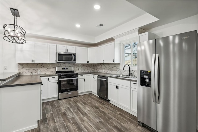 kitchen with pendant lighting, white cabinets, sink, appliances with stainless steel finishes, and dark hardwood / wood-style flooring