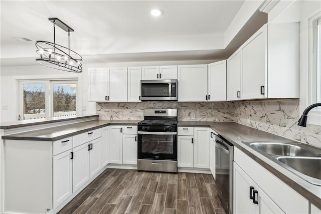 kitchen with stainless steel appliances, dark wood-type flooring, sink, a notable chandelier, and white cabinetry