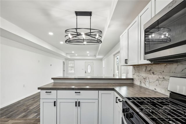 kitchen featuring white cabinets, dark hardwood / wood-style flooring, range, and hanging light fixtures