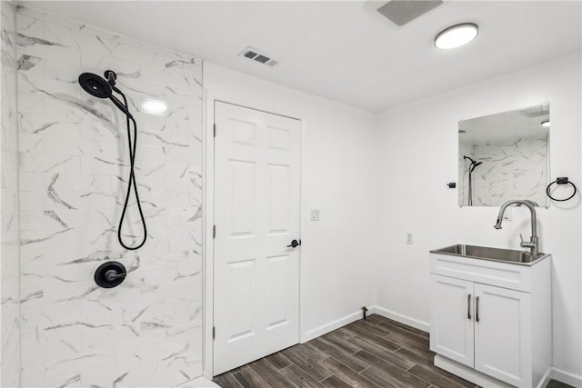 bathroom with tiled shower, vanity, and hardwood / wood-style flooring