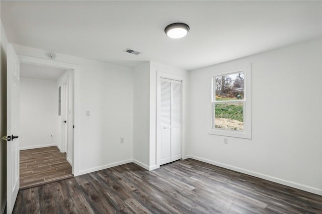 unfurnished bedroom with dark hardwood / wood-style floors and a closet