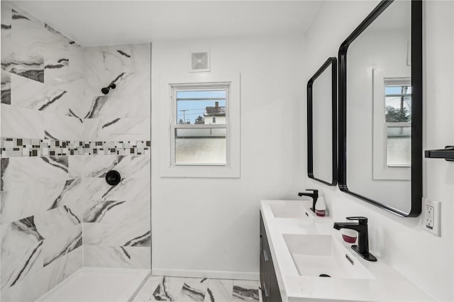 bathroom with a tile shower and vanity