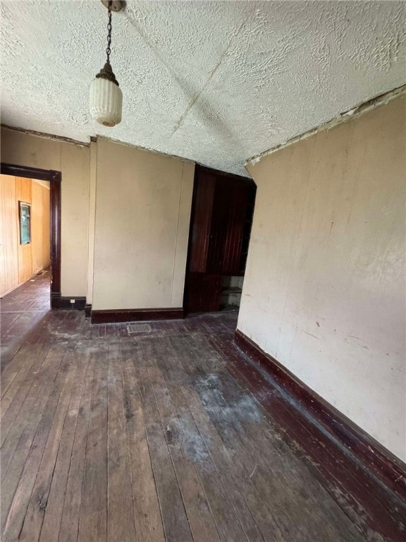 empty room featuring dark hardwood / wood-style flooring and a textured ceiling