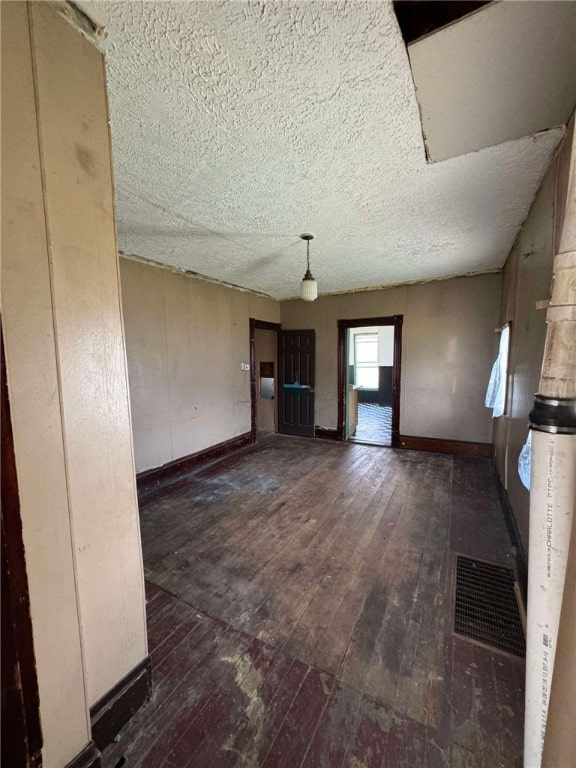 unfurnished living room with a textured ceiling and dark wood-type flooring