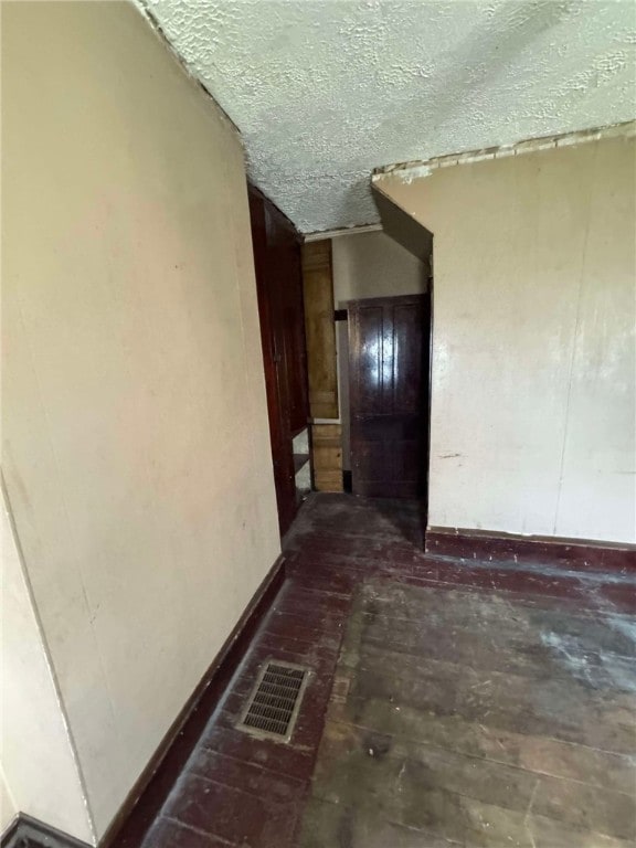 hall with a textured ceiling and vaulted ceiling