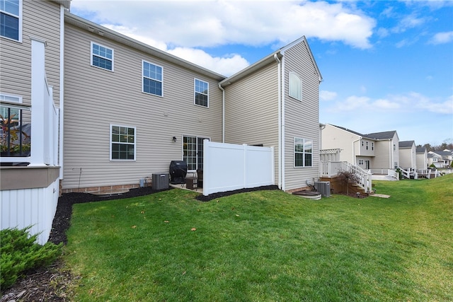 back of property with central air condition unit and a lawn