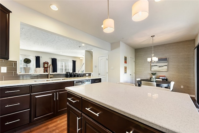 kitchen with dark brown cabinetry, dark hardwood / wood-style floors, hanging light fixtures, and sink