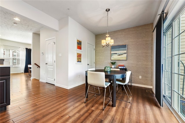 dining area with dark hardwood / wood-style flooring and an inviting chandelier