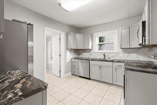 kitchen with appliances with stainless steel finishes, backsplash, gray cabinetry, sink, and light tile patterned floors