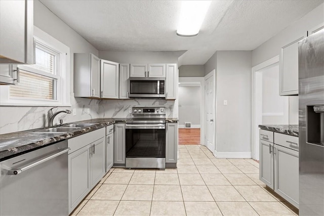 kitchen with appliances with stainless steel finishes, a textured ceiling, gray cabinetry, and sink