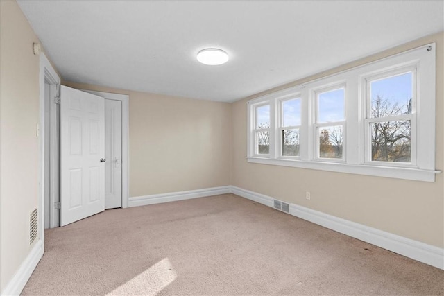 unfurnished room with a wealth of natural light and light colored carpet