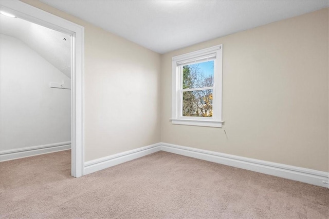 spare room with light colored carpet and lofted ceiling