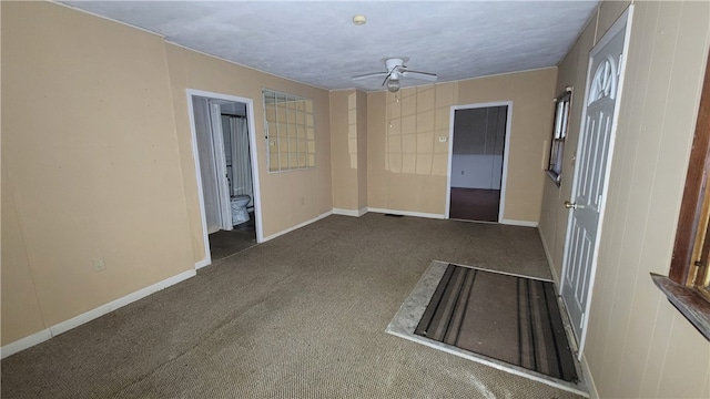 spare room featuring ceiling fan, dark carpet, and a textured ceiling