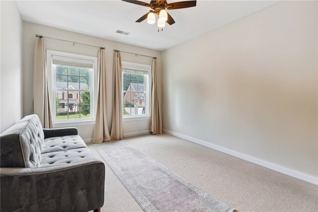 living area with light colored carpet and ceiling fan