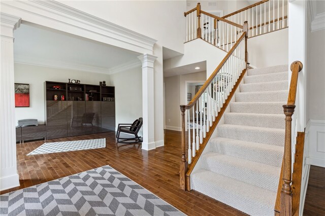 foyer featuring ornamental molding, dark wood-type flooring, and ornate columns