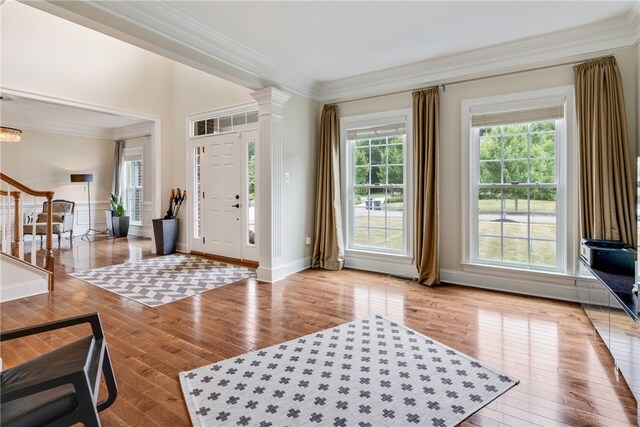 entrance foyer featuring decorative columns, crown molding, and light wood-type flooring