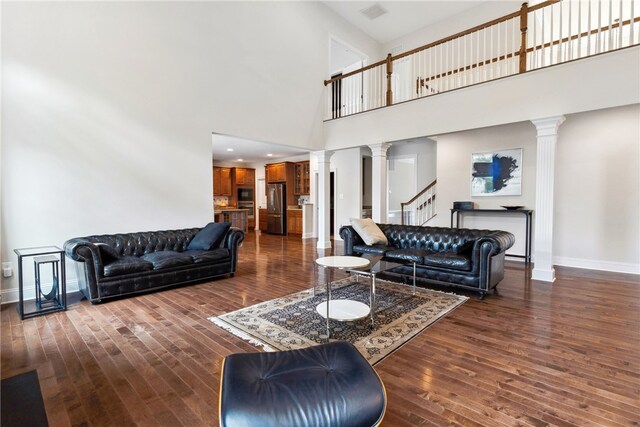 living room with dark hardwood / wood-style flooring, a high ceiling, and decorative columns