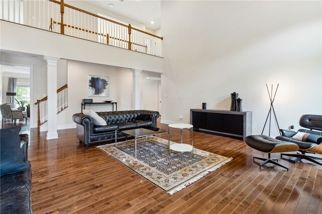 living room featuring ornate columns, dark hardwood / wood-style flooring, and a high ceiling