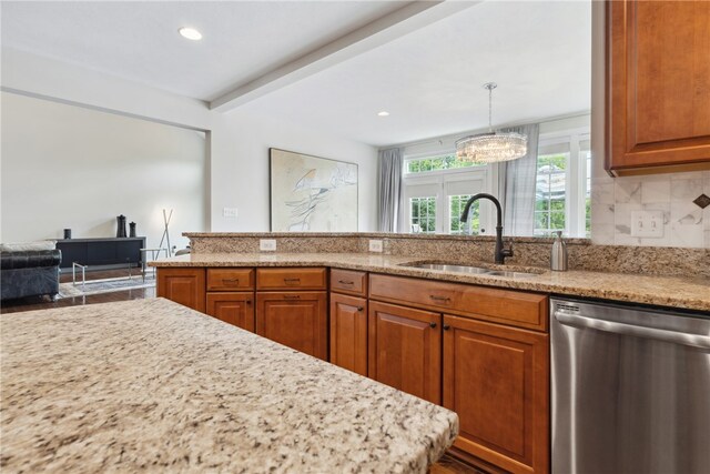 kitchen featuring dishwasher, sink, light stone counters, backsplash, and decorative light fixtures