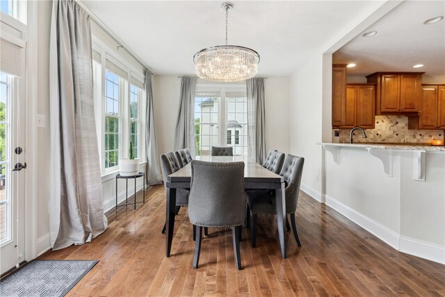 dining space with a chandelier, wood-type flooring, and sink